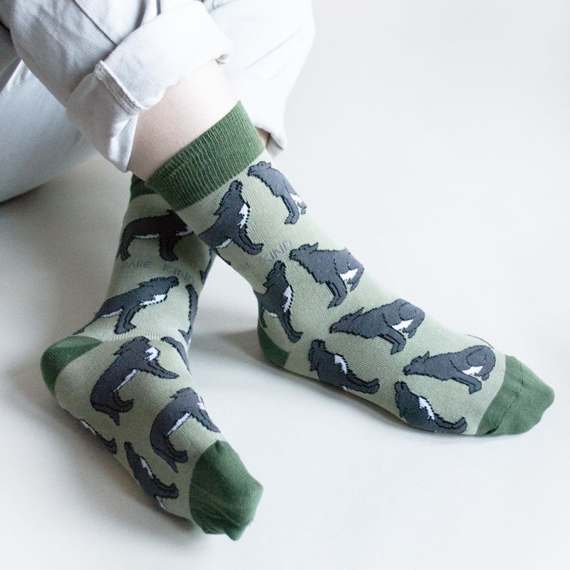 Green socks with wolf pattern worn by a person on a white background