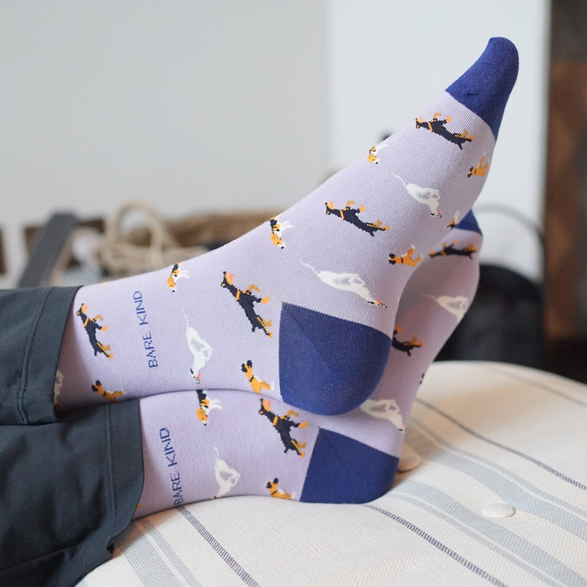 Person wearing socks with dog pattern and 'Barefoot Kind' branding on a blurred background